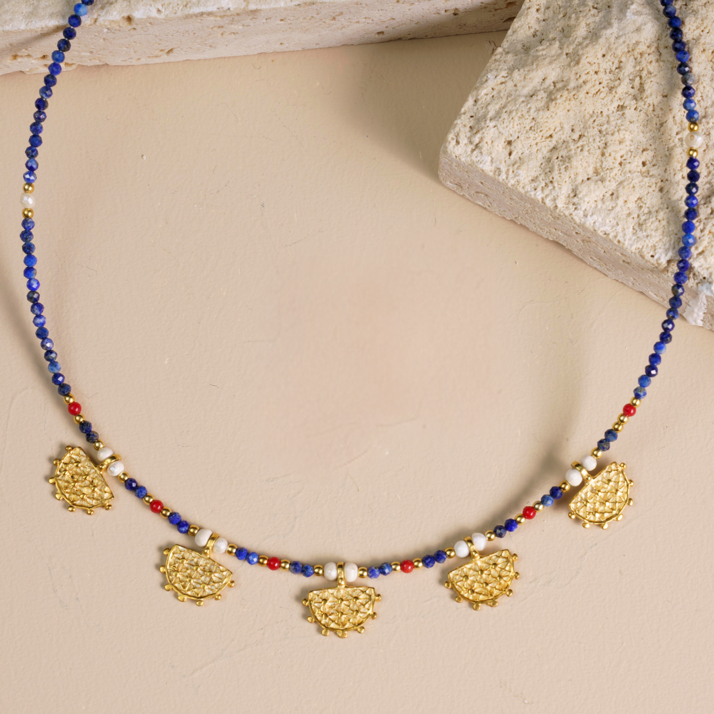 Hittite Sun Symbol necklace with Lapis Lazuli gemstones, featuring intricate gold-toned detailing on a neutral background.