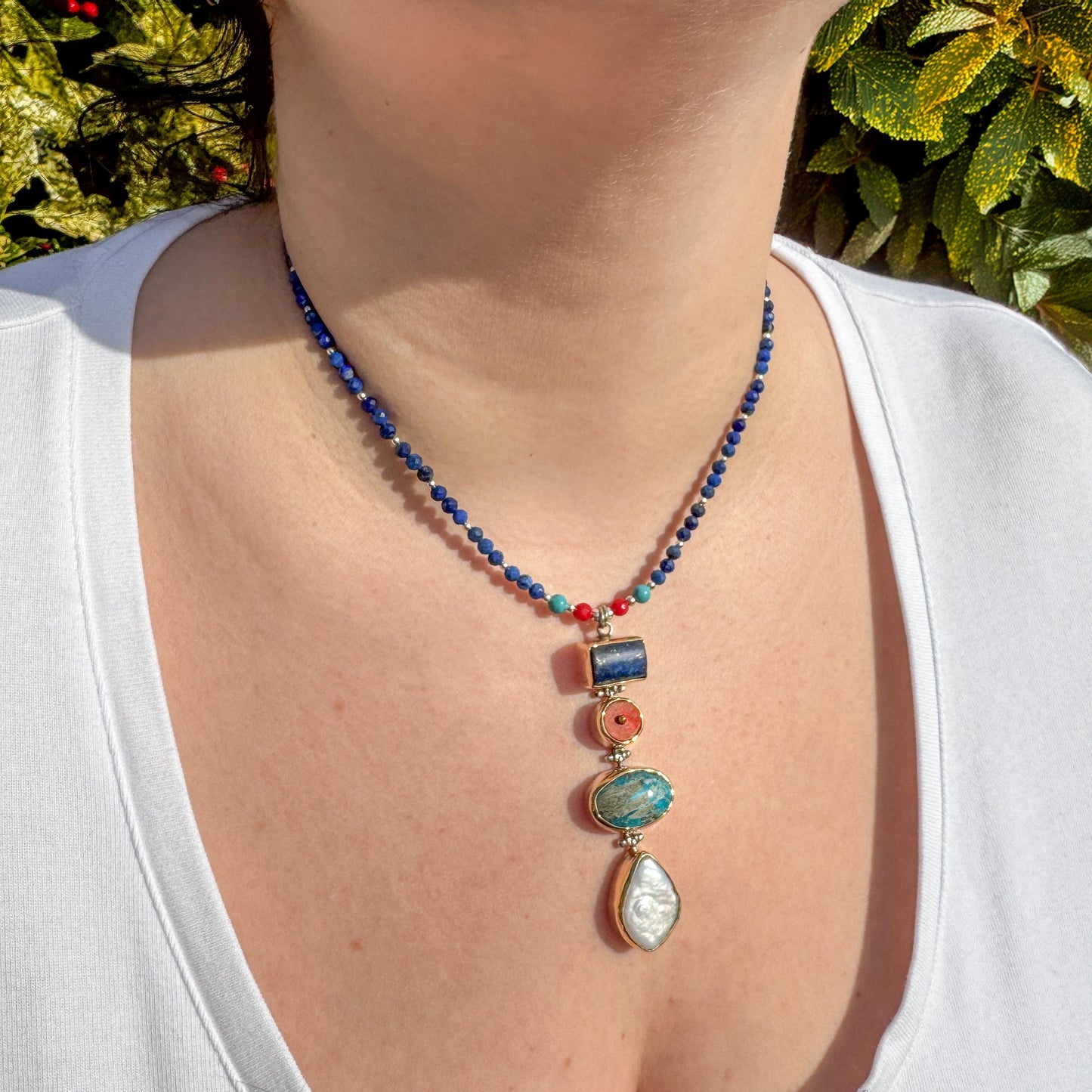 Elegant necklace showcasing lapis lazuli, coral, and turquoise gemstones, worn stylishly for a radiant look.