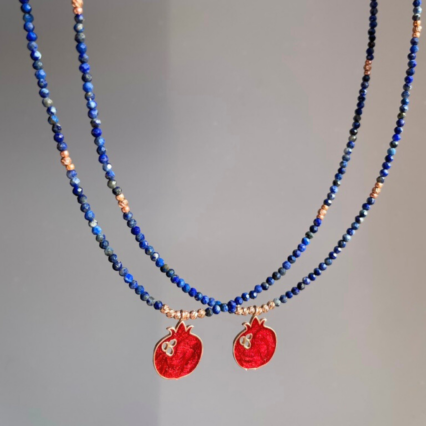Elegant red pomegranate lapis necklace with intricate design, featuring vibrant blue lapis beads and small red pendants.