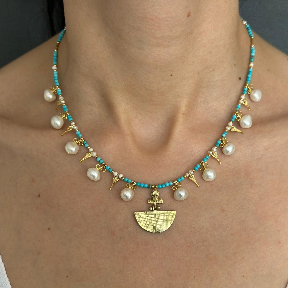 Selena Turquoise Necklace and Earrings Set - 14K Gold Plated with turquoise beads, pearls, and unique gold pendant, worn by a woman.