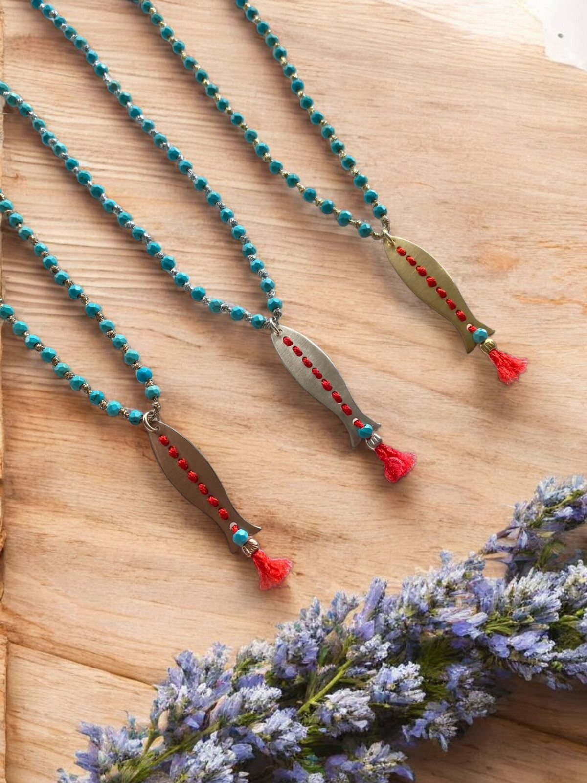 Afrodit Fish Pendant Long Necklace in 925 Silver with turquoise beads and red tassels on wooden surface with lavender