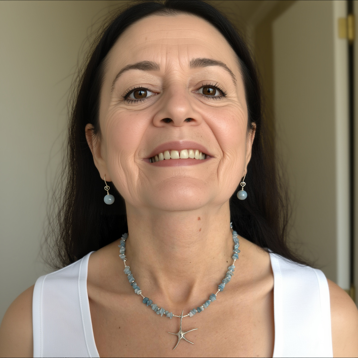 Woman wearing an aquamarine starfish necklace crafted in sterling silver, showcasing a stylish handmade jewellery piece.