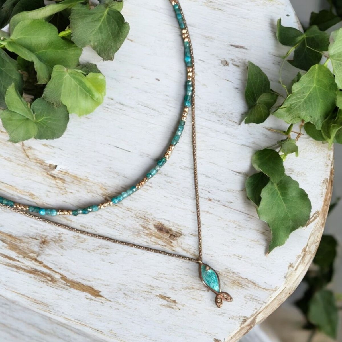 Azure Silver Fish and Apatite Gemstone Necklaces elegantly displayed on a rustic white background.
