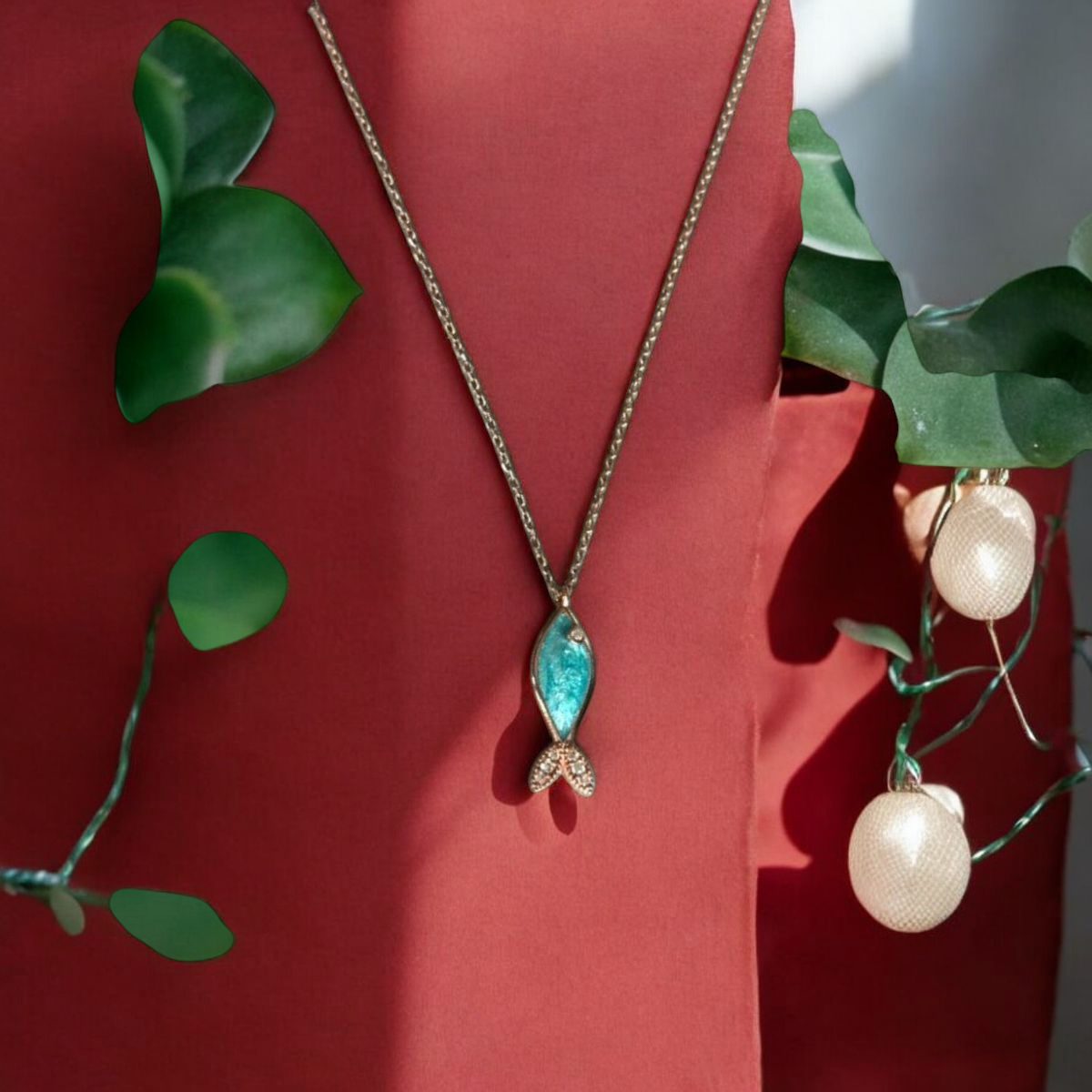 Azure Silver Fish Necklace with Rose Gold Plating, handcrafted design, displayed against a rich red background.