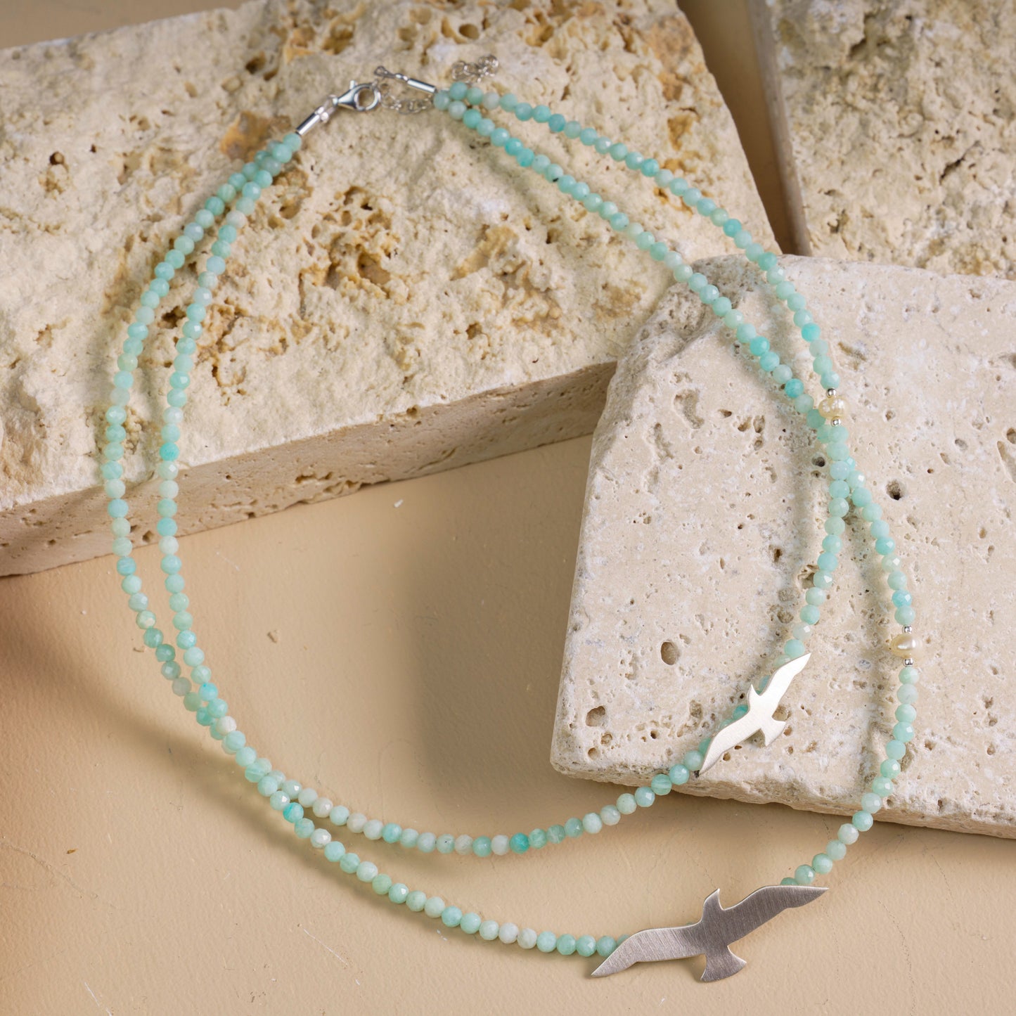 Elegant seagull Amazonite necklace with silver detailing, perfect for a stylish and natural look, laid on stone surface.