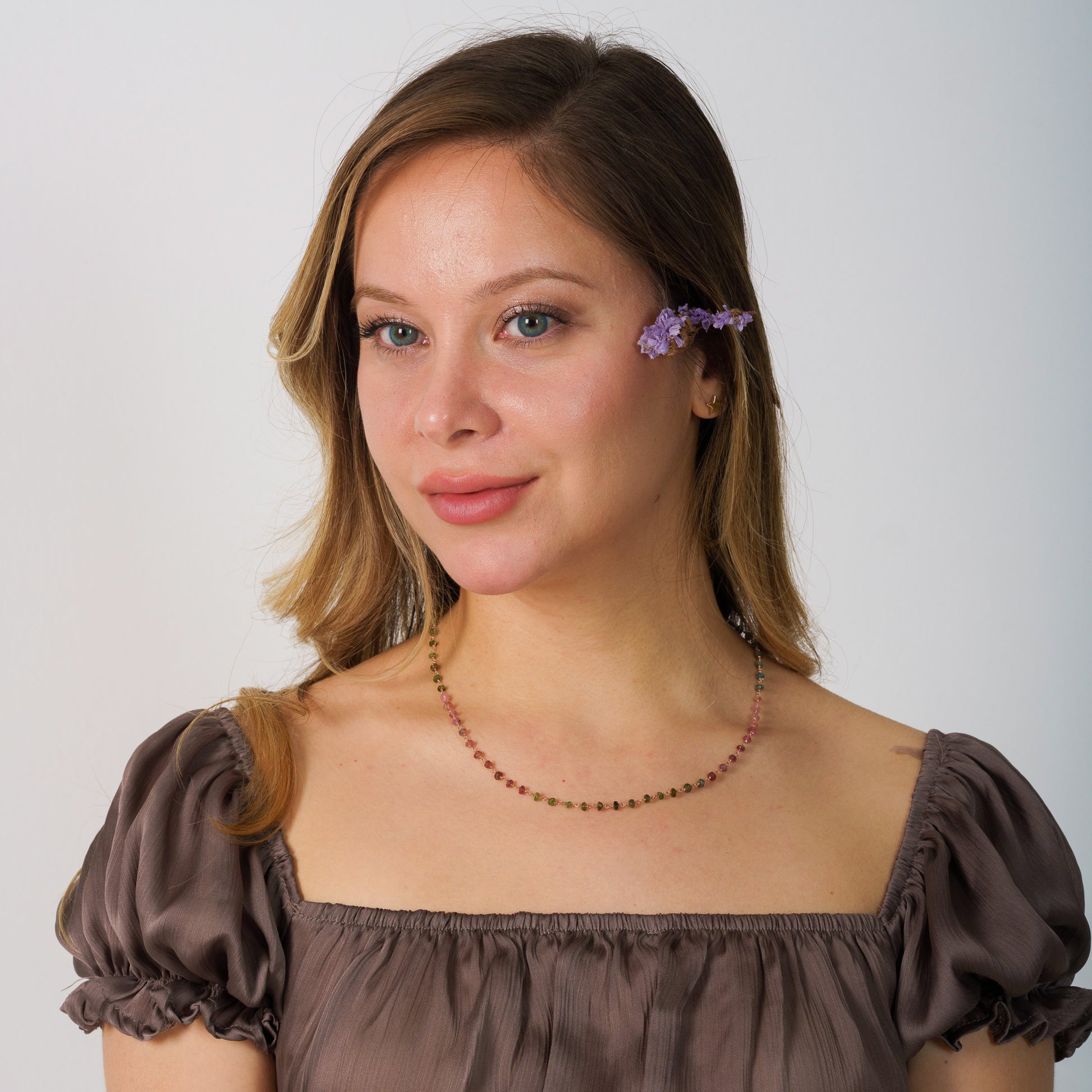Model wearing a dainty chain necklace with multicolour tourmaline gemstones, paired with a sophisticated outfit.