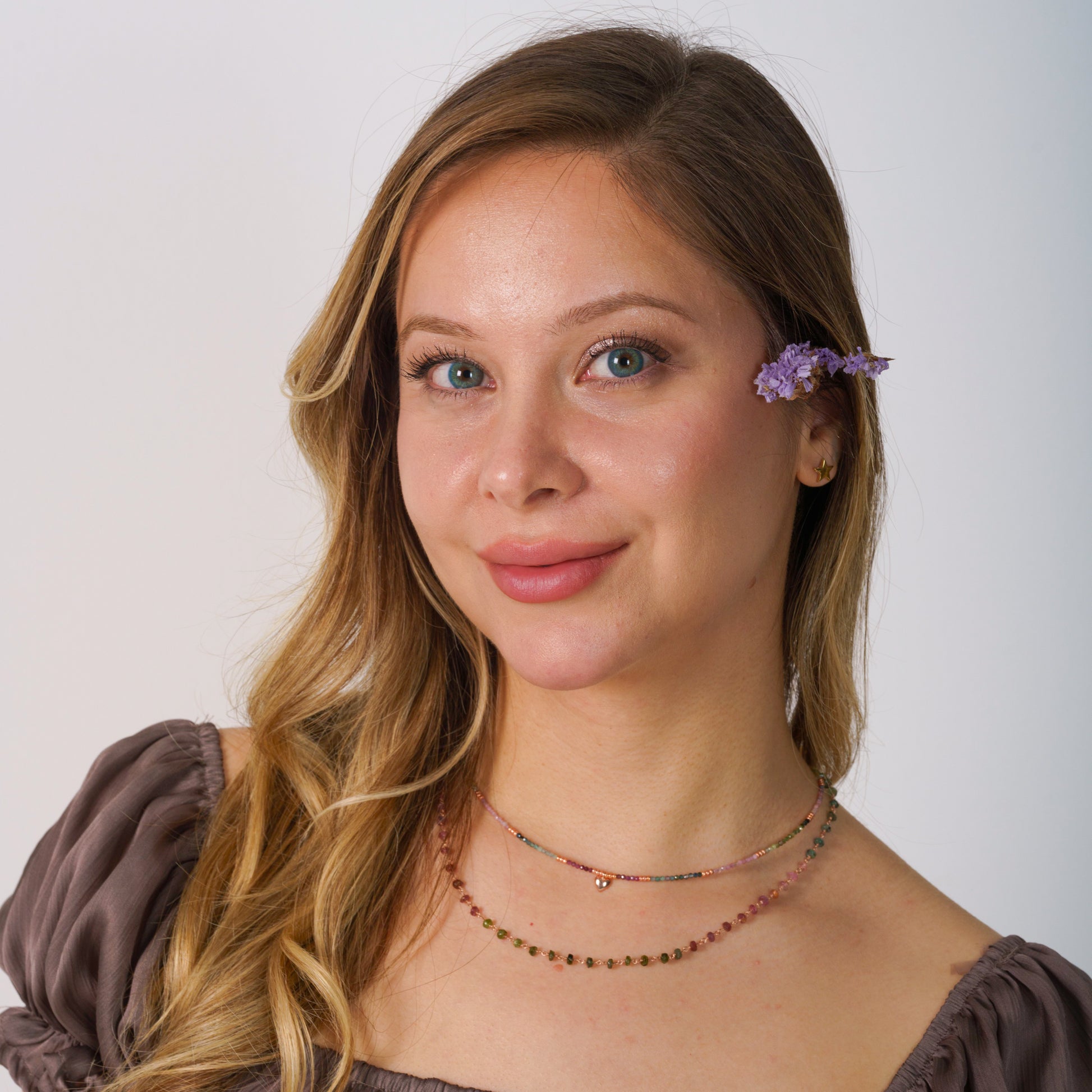 Elegant woman wearing a dainty multicolour tourmaline gemstone chain necklace, styled with a soft, sophisticated outfit.