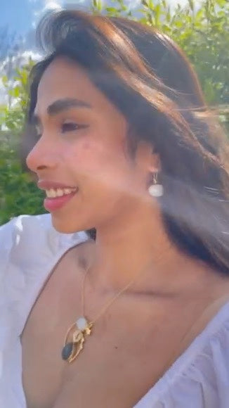 Model wearing the Day and Night Moonstone Silver Necklace with complementing attire in a sunlit outdoor setting.