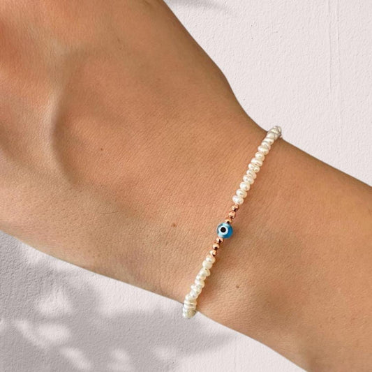 Elegant freshwater pearl bracelet with a delicate mini evil eye charm, a timeless and stylish accessory for any outfit.