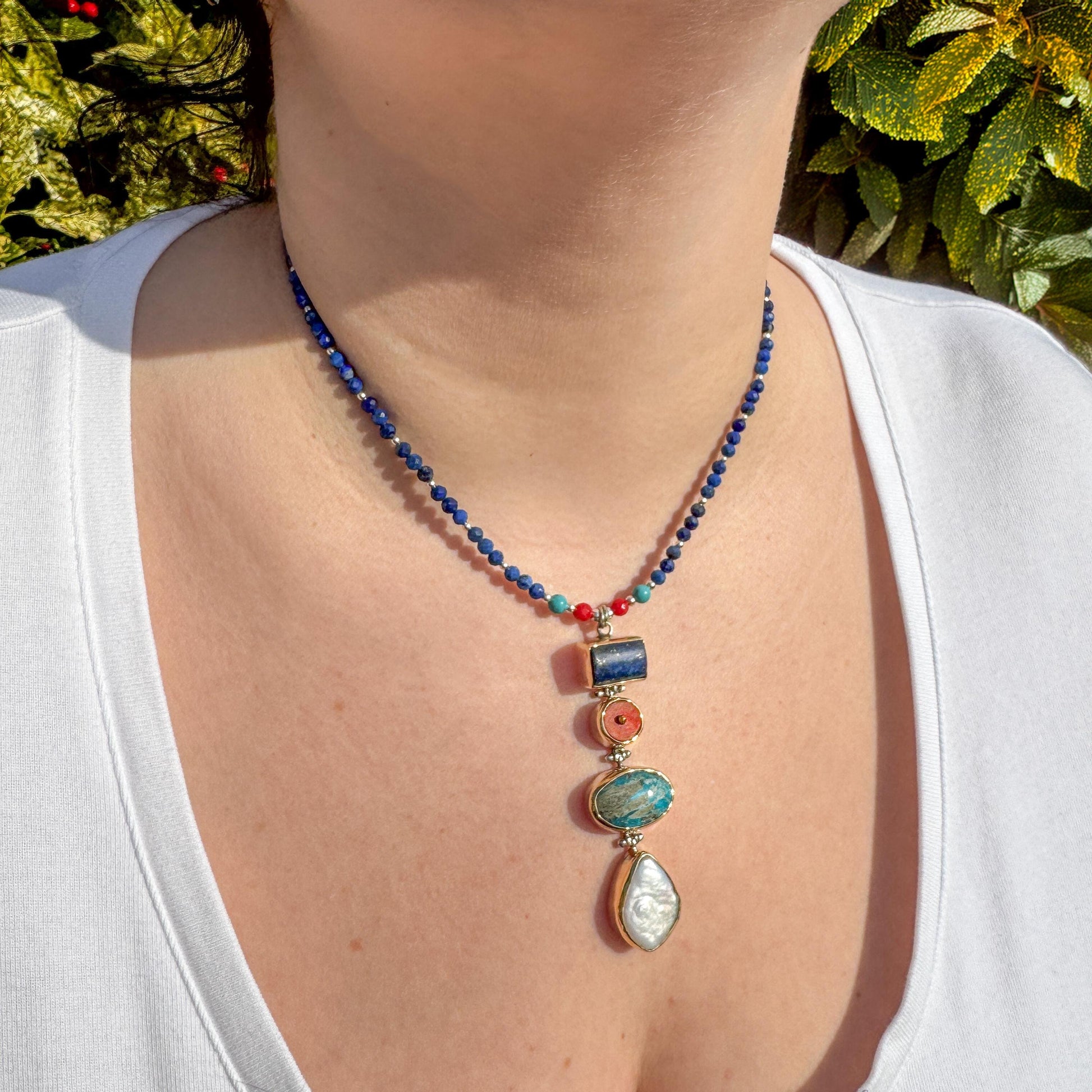 Elegant necklace showcasing lapis lazuli, coral, and turquoise gemstones, worn stylishly for a radiant look.