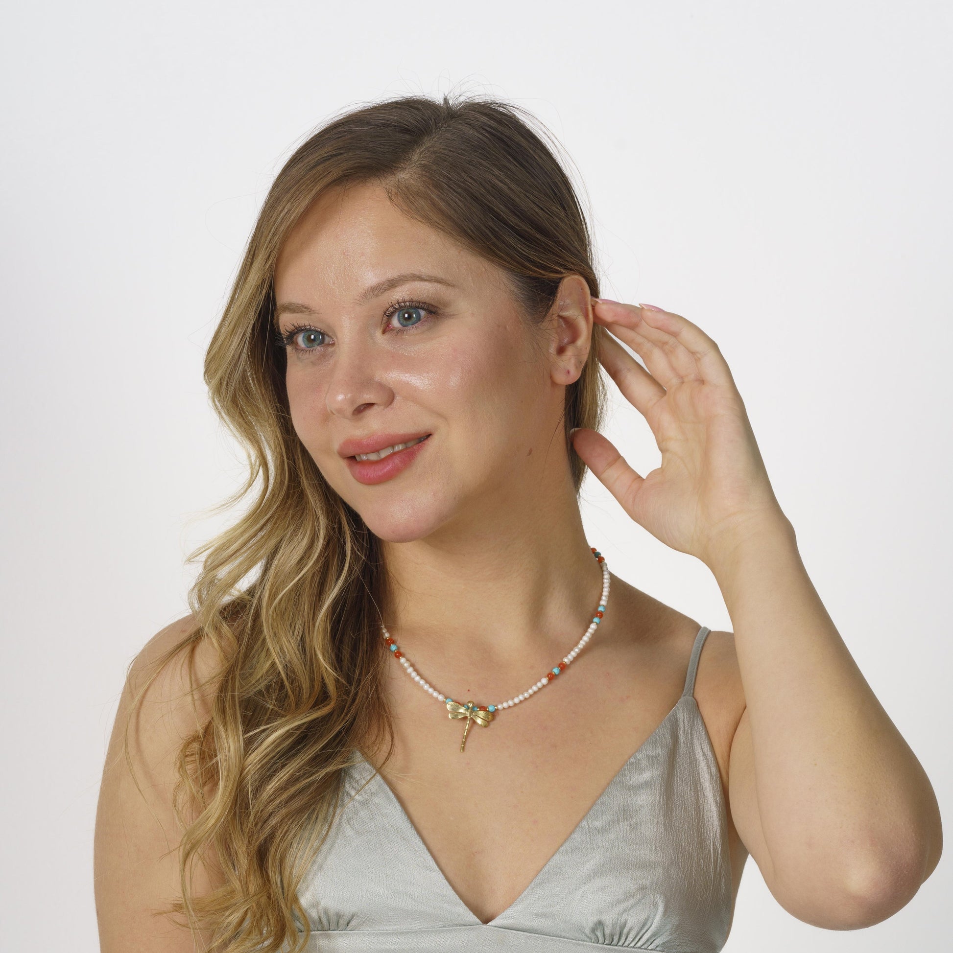 Elegant pearl and gemstone necklace featuring a silver dragonfly pendant, beautifully worn with a stylish outfit.