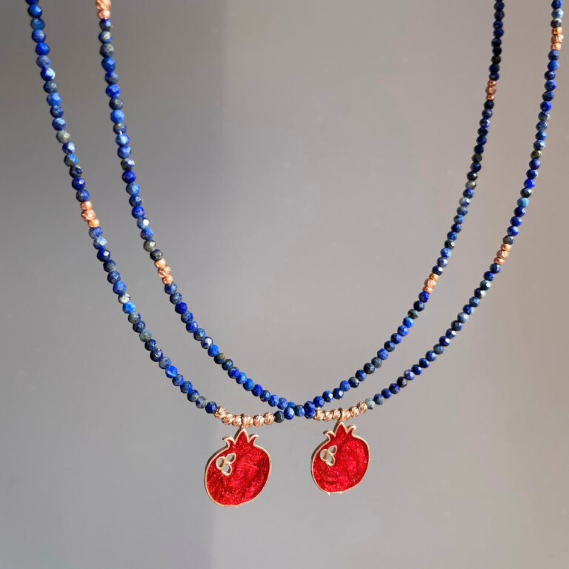 Elegant red pomegranate lapis necklace with intricate design, featuring vibrant blue lapis beads and small red pendants.