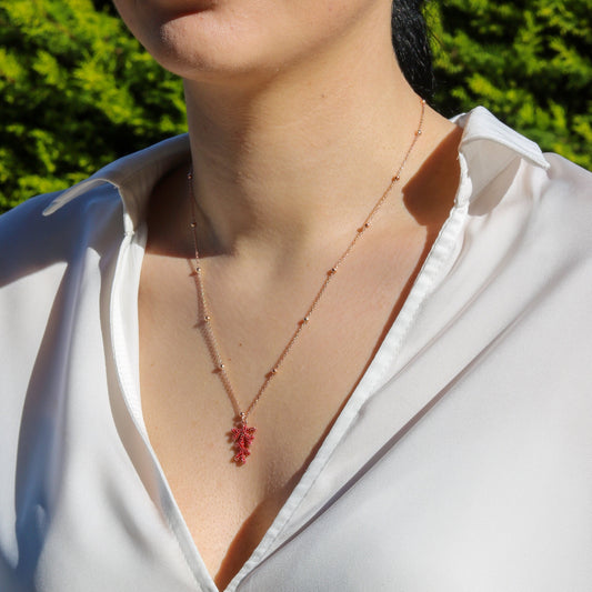 Rose gold plated silver chain with red coral pendant worn by a woman in a white shirt.