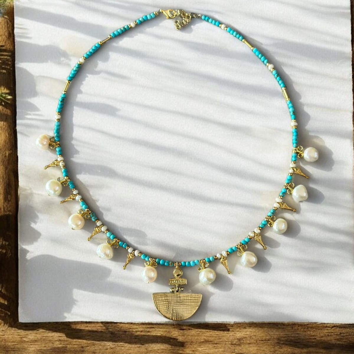 Selene Turquoise Gemstone and Pearl Necklace - Gold Plated displayed elegantly with delicate shadows.